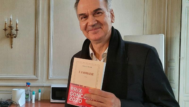 Hervé Le Tellier, lauréat du Prix Goncourt pour L'Anomalie, souriant avec son roman